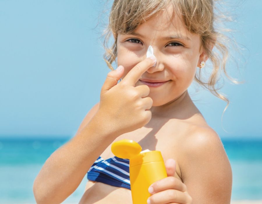 Kleinkind mit Sonnenschutz am Strand